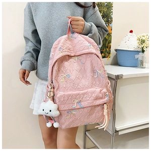 Detailed side view of pink quilted backpack with butterfly embroidery and cloud charm
