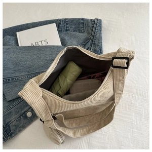 Detail view of corduroy crossbody bag interior showing large capacity for umbrella and wallet