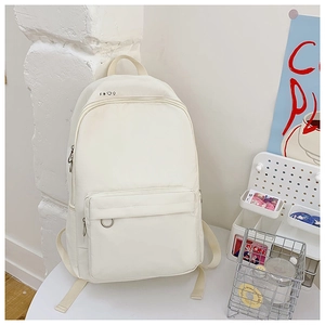 Detailed view of the white canvas backpack front pocket and minimalist small icon logo