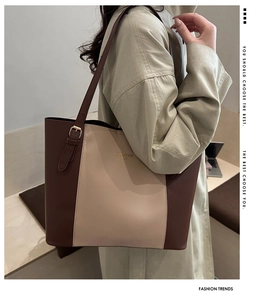 Detail view of contrast color tote bag with adjustable gold buckle and brand logo