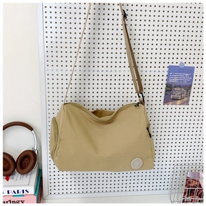 Detail view of khaki nylon crossbody bag hanging on pegboard with retro accessories
