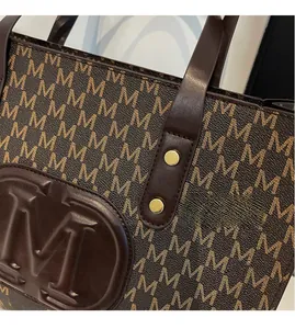 Close-up of dark brown tote bag with Monogram M print and golden metallic rivet details