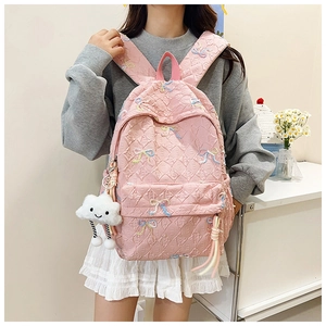 Detailed view of a pink quilted backpack with colorful embroidery and a plush cloud charm