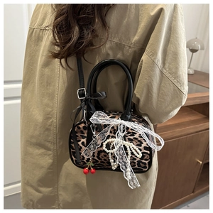 Detail of leopard print handbag with white lace bow and elegant pearl chains in hand