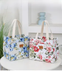 Close-up of floral canvas tote bags with leather logos on a white table in home setting