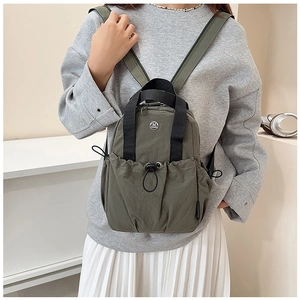 Close-up of olive green nylon backpack with drawstring pocket and metallic logo detail
