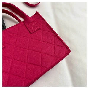 Detailaufnahme der fuchsiafarbenen Stepptasche mit Rautenmuster und Filzoberfläche