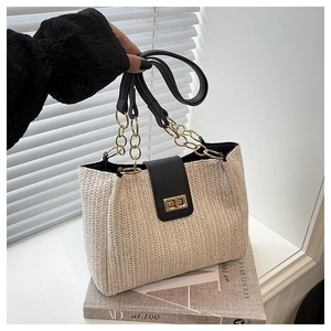 Detailed close-up of woven tote bag with black leather flap and golden twist lock