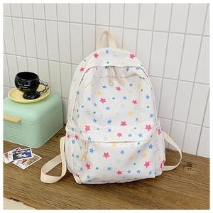 Detail of white canvas backpack with colorful star prints on a wooden table setup
