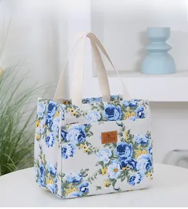 Close-up of blue floral canvas tote bag with a brown leather logo and woven handles