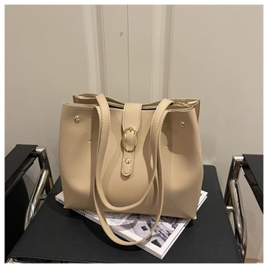 Detail of minimalist beige faux leather tote bag with golden oval buckle on office chair