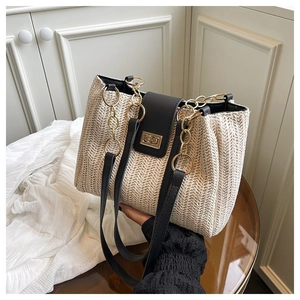 Detail of herringbone weave texture, gold clasp and black leather straps on a tote bag