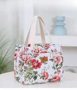 Detail of floral canvas bento bag with brown leather tag and sturdy woven handles