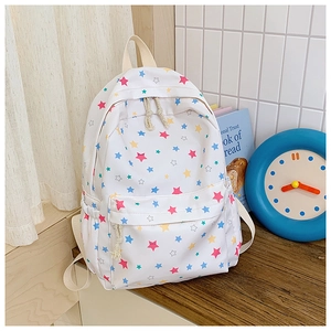 Detailed close-up of a white canvas backpack featuring colorful star patterns and a front pocket