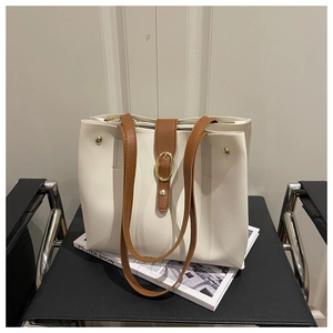 Detail of white tote bag with brown leather strap and gold buckle on a chair