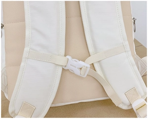Close-up of beige breathable mesh back and white nylon straps with plastic chest buckle