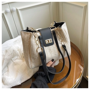 Detailed macro view of woven beige tote bag featuring gold metal turn-lock and chain handle