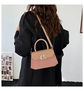 Sac bandoulière tissé chic avec motifs roses et boucle dorée en M porté par le mannequin