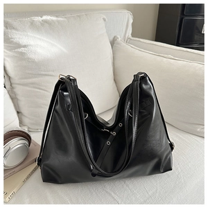 Detail of minimalist black large-capacity tote bag in premium PU leather on white sofa