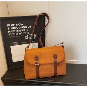 Close-up of vintage brown suede messenger bag with leather straps and golden buckles