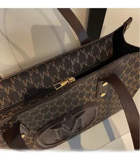 Detailed close-up of the smooth golden zipper and refined M-pattern stitching on tote bag
