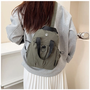Detail of olive green nylon backpack with drawstring pocket and metallic M logo
