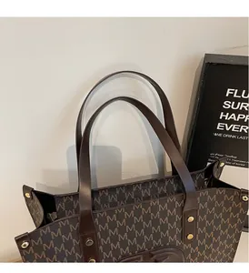 Close-up of the reinforced leather handle and golden rivet hardware on the tote bag