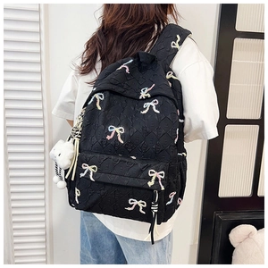 Detail view of black quilted backpack with colorful bows and plush cloud keychain
