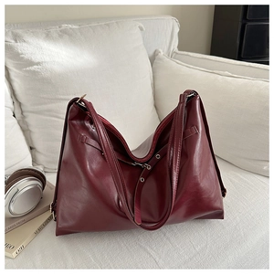 Detail of burgundy faux leather tote bag with silver metal eyelets and soft texture