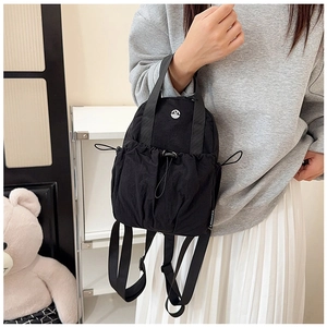 Detail of waterproof nylon backpack featuring a drawstring front pocket and a metal logo