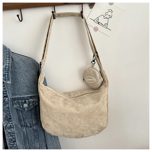 Detail of beige corduroy crescent crossbody bag with mini round coin purse pendant