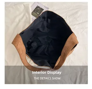 Top view of spacious black fabric lining inside a brown suede tote bag with magazine