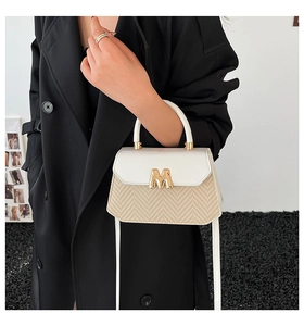 Vue détaillée de la texture tissée et de la boucle dorée M sur le sac bandoulière élégant