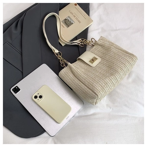 Detail of beige woven tote bag with gold chain strap and metallic twist-lock closure