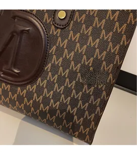 Detail view of M-pattern monogram tote with embossed leather logo and gold hardware