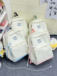 Detail of four colorful pastel backpacks with ribbon bows and cute wing tags for students