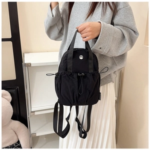 Detail of black nylon mini backpack with side drawstring pocket and metal logo detail