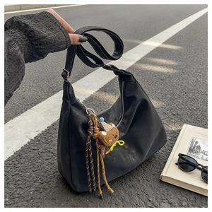 Detail of black suede crescent bag with cute bear charm and silver metal zipper