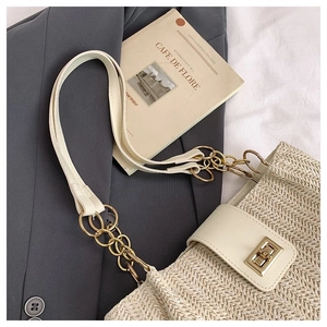 Close-up of woven straw tote bag with elegant gold metal twist lock and leather chain strap