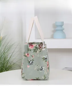 Detail of green floral canvas lunch bag with cream ribbon handles in a home setting