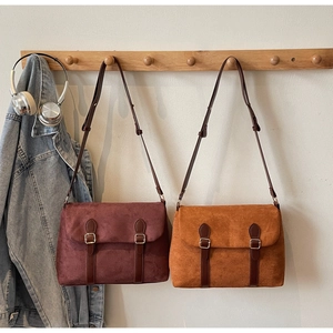 Retro faux suede crossbody bags in dark red and tan with leather straps on a wooden hanger