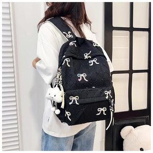 Detail of black backpack with colorful bow embroidery and a cute cloud plush charm accessory