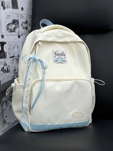 Detail view of the white and light blue canvas backpack featuring a lace bow and brand patch
