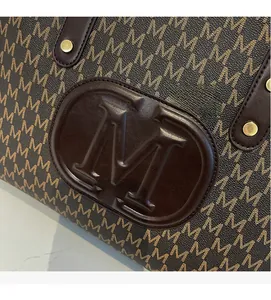 Detailed macro view of monogram print, embossed logo, and gold rivets on a tote bag