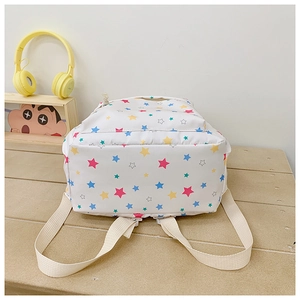 Close-up of white canvas backpack with colorful star patterns and cotton straps on a bench