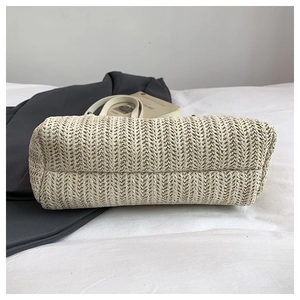 Detailed macro view of the woven V-pattern bottom on this beige large straw tote bag