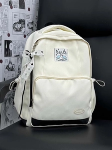 Close-up of beige canvas backpack with black base and ribbon bow detail