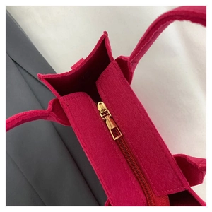 Detail der rosaroten Filztasche mit goldenem Metallreißverschluss und Textur des Filzes