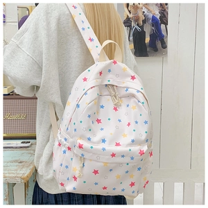 Detail of white star printed backpack showing the colorful patterns and front zipper pocket