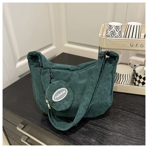 Detail of dark green corduroy hobo bag texture with a round fashion coin purse charm
